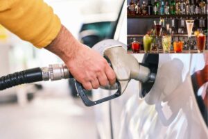 Un'auto al rifornimento e alcuni cocktail sul bancone di un bar